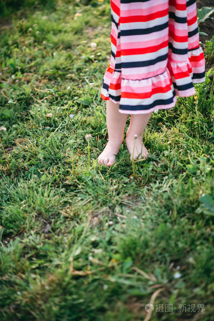赤脚女孩在衣服上站在草地上特写