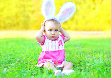 快乐可爱的宝宝，在阳光明媚的春天天草地上的兔耳朵