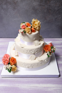 装饰着花朵在灰色的背景上的白色婚礼蛋糕