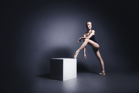 年轻的芭蕾舞演员在深色布跳舞在漆黑的照像馆