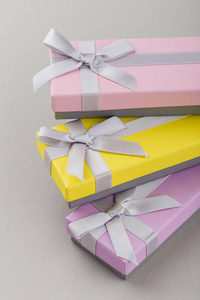 彩色礼品盒与丝带弓灰色背景。粉红色, 黄色和紫色的长盒子。节日礼物
