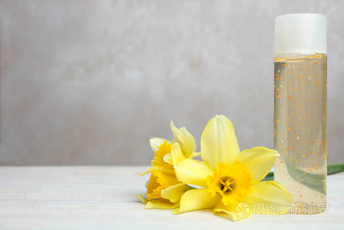 中性背景下木桌上的沐浴露和水仙花