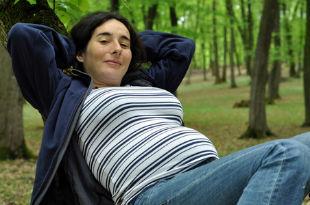 在森林里放松的平静怀孕女人