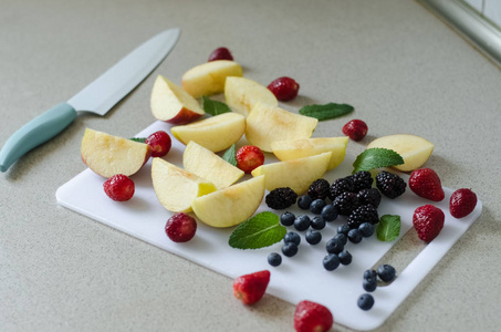 切片新鲜的苹果, 草莓, 蓝莓和黑莓, 薄荷叶周围, 新鲜的夏季水果, 厨房刀边