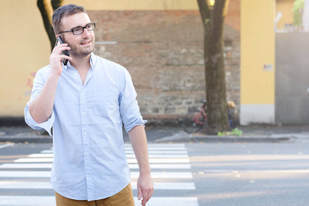 缺乏道路呼吁他的智能手机和走在城市街道上的人照片