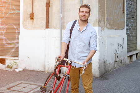 时尚男人的抱着他的自行车在城市街头