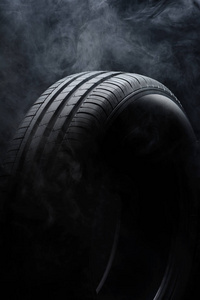 汽车轮胎和黑色背景上的烟