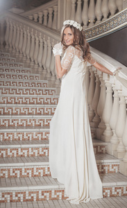 美丽优雅的女孩，在一条白色的裙子站在城堡的老式楼梯上
