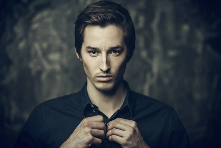 超过男子特写肖像的黑头发的年轻男子在蓝色衬衫超过黑暗背景.