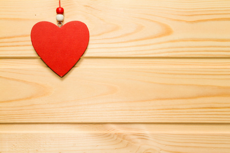 木制的红色的心形，悬挂在一个天然的木材背景上。Valentin