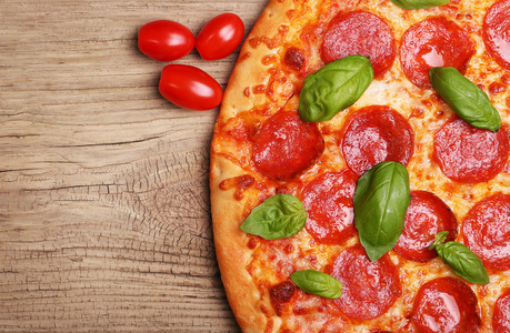意大利辣香肠比萨饼与罗勒和番茄木背景
