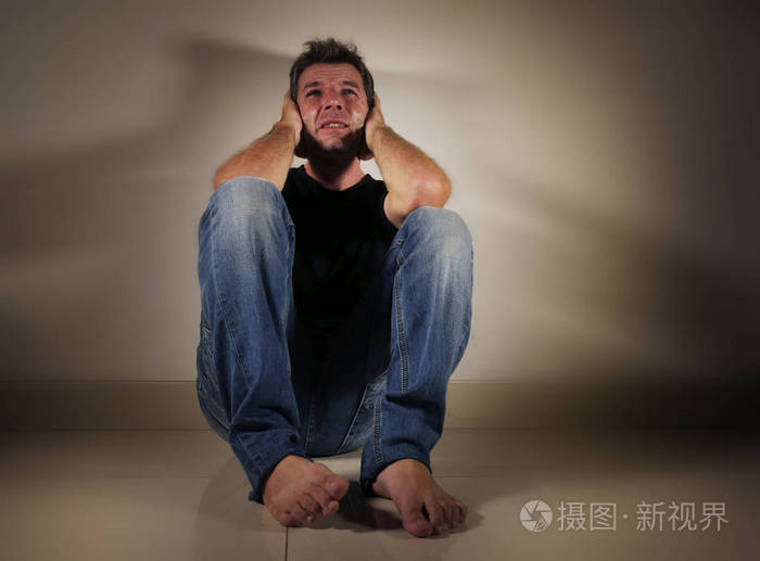 男人哭泣悲伤坐在家里地板上的阴暗和戏剧性的工作室光看悲伤和沮丧