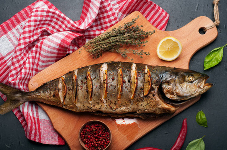 烤的鱼金枪鱼用草药, 香料和柠檬片,躺在砧板上烤金枪鱼 (鱼).