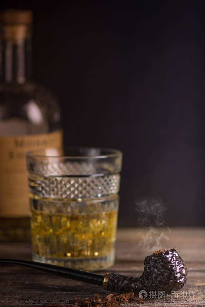 烟草在木桌上的高高的玻璃上刻着深褐色的烟烟斗和威士忌照片-正版