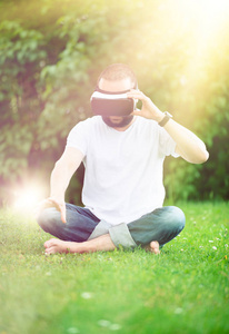 年轻人有胡子的人穿上虚拟现实的护目镜，坐在他的花园。生活方式 Vr 乐趣和放松的概念