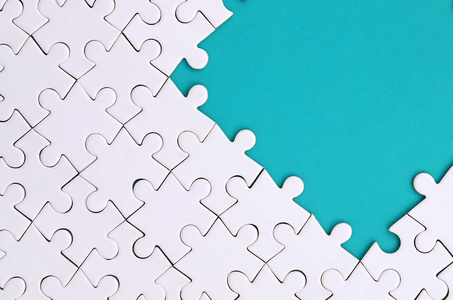 在蓝色塑料表面的背景下折叠的白色拼图拼图碎片.