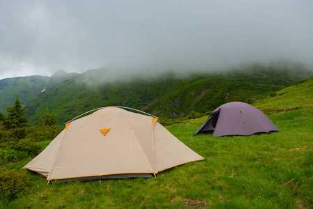 帐篷在绿色山草甸在背景绿色脊在雾在山在风暴之前