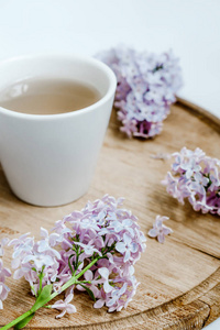 丁香花和木材交付桌子上的茶一杯。白色背景