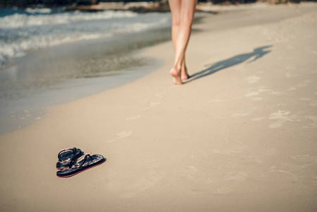那女孩赤脚沿着海滩走。沙子上的触发器