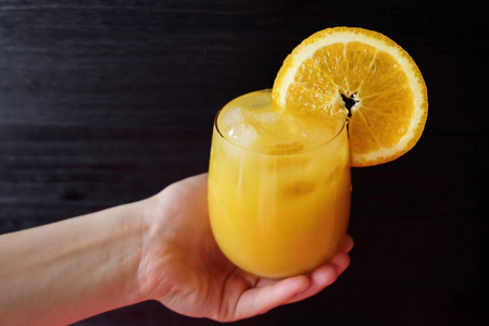 橙汁在深色背景上的手