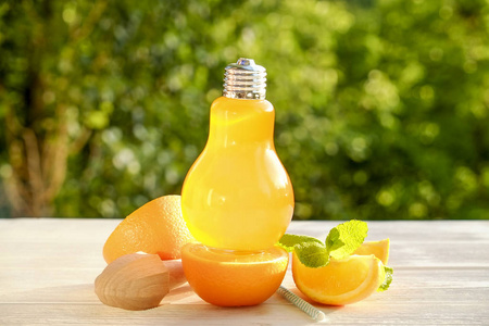 一个灯泡形状的玻璃自制冰柠檬水, 片有机柠檬和橙, 薄荷, 榨汁机在白色的木桌上, 国家边的树叶背景。关闭, 顶部视图, 复制空