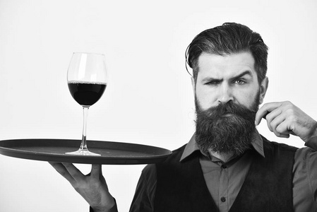 酒保用严厉的面孔举行酒精饮料卷曲的胡子。服务餐饮理念。胡子男人