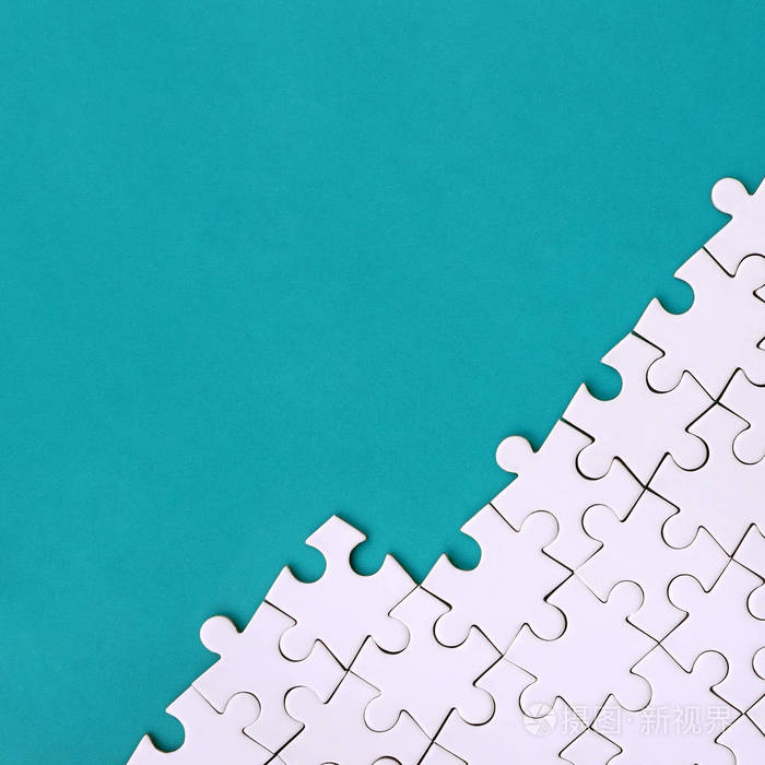 在蓝色塑料表面的背景下折叠的白色拼图拼图碎片.