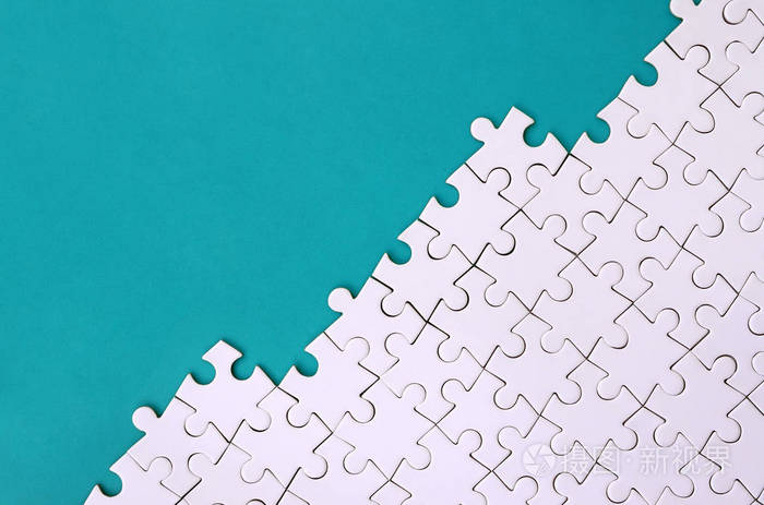 在蓝色塑料表面的背景下折叠的白色拼图拼图碎片.