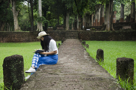 旅行者泰国妇女步行参观和旅行照相在古建筑和废墟烹 Phet 历史公园是一个考古学地点和 Aranyik 地区在烹 Phet, 泰