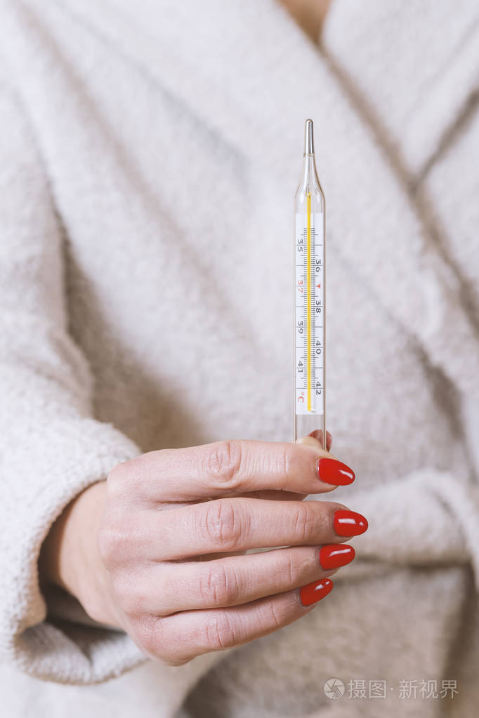 手持体温计的妇女, 在患流感时测量体温