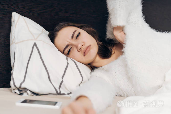 一个不满的年轻女孩在睡衣醒来早, 躺在床上, 不想起床