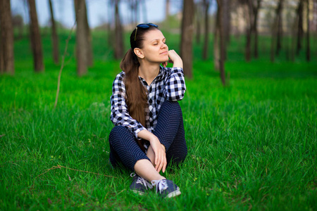 漂亮的女人们在公园里休息, 坐在绿色的草地上.