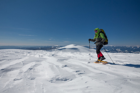 徒步旅行者在冬天山雪地行走在阳光灿烂的日子
