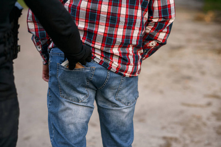 小偷穿着黑色的衣服和手套从口袋里偷钱的钱包.白天在街上扒窃照片