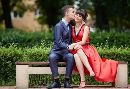 年轻夫妇坐在长椅上亲吻