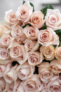 柔和的粉红色玫瑰。一束美丽的花朵在木桌上。植物概念。花店里花匠的工作。垂直照片