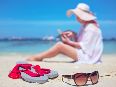 在热带海滩上使用智能手机的放松的女人