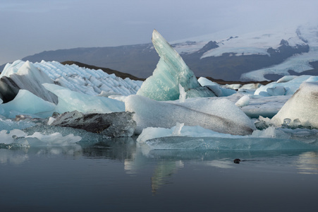 冰块在 Jokulsarlon 冰川泻湖与雪山脉背景