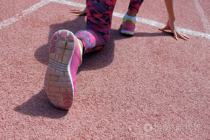 在跑步机的白色起跑线前, 一个女孩腿上的粉红色运动鞋的鞋底特写.
