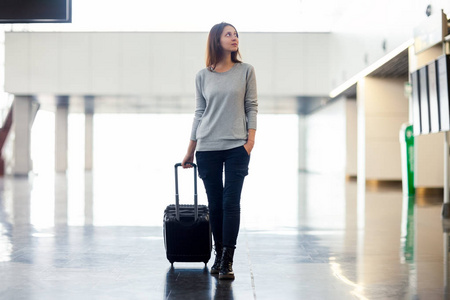 在机场候机楼有手提箱的年轻女子。旅游理念