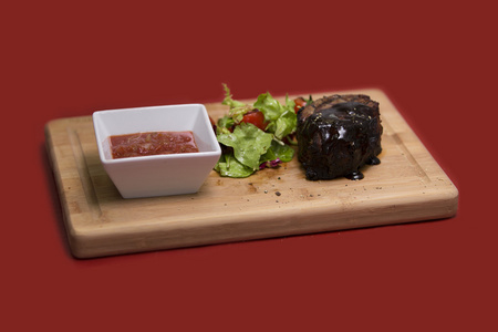 木制的桌子上的美味牛排特写。与蔬菜在砧板上的烤的小牛排