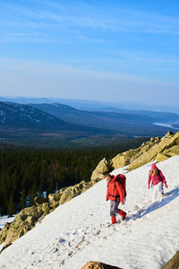 在阳光明媚的日子里, 背囊的游客在山上的雪坡上降落。