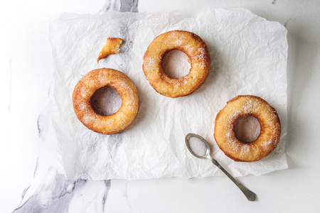 自制的粉扑油炸油炸圈饼或 cronuts 与糖在皱纸上的白色大理石纹理背景。平躺, 空间