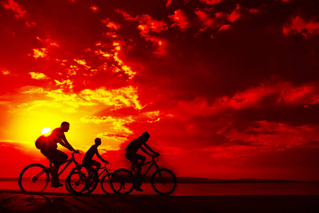 空的空间。运动的朋友在自行车在日落。骑自行车的人沿着海岸。体育在自然背景