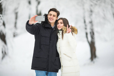 男人以自拍照照片年轻对浪漫的情侣微笑雪森林户外冬季松林.