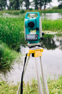 测量设备全站仪在湖泊和森林背景上的蓝色