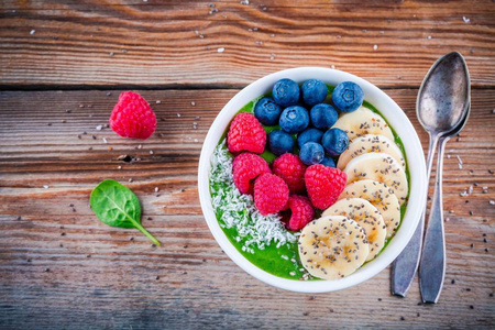 健康早餐碗 香蕉 蓝莓 覆盆子 正大种子和椰子绿色菠菜思慕雪