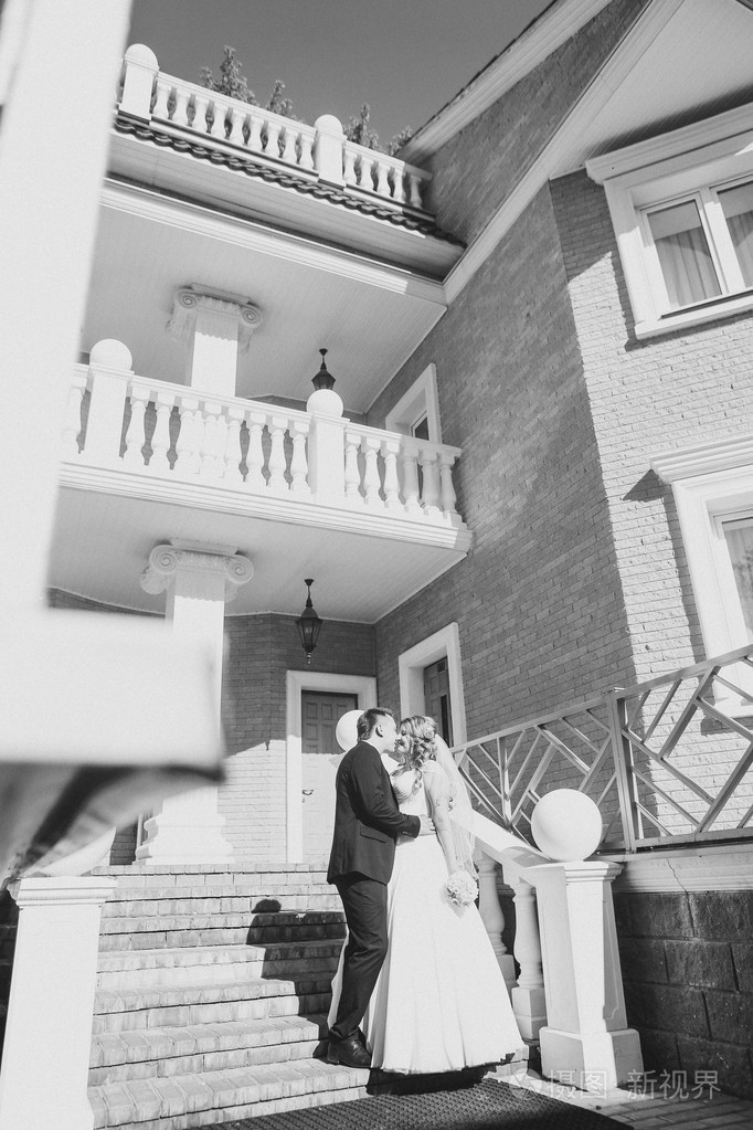 新娘和新郎拥抱他们站在背景上的市全长美丽的建筑