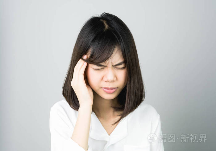 穿白色连衣裙的女人摸头, 露出头疼的样子.