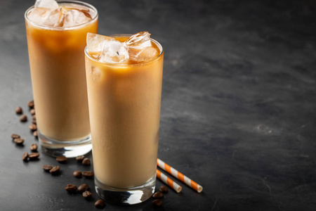冰咖啡在一个高的玻璃与奶油浇过, 红糖和咖啡豆。寒冷的夏天在黑暗的背景下喝酒。具有复制空间